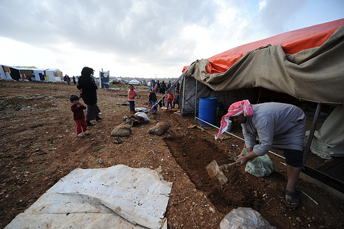 Hussein digs outside his tent near Amman to prevent flooding